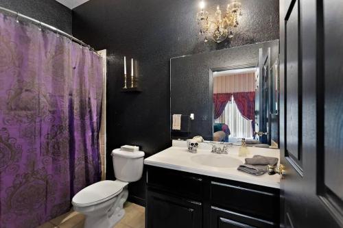 基西米A Spooktacular Haunted Mansion.的浴室配有水槽、卫生间和紫色淋浴帘