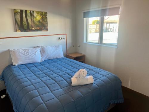 费尔利松林汽车旅馆的一间卧室配有一张蓝色的床,上面有毛巾