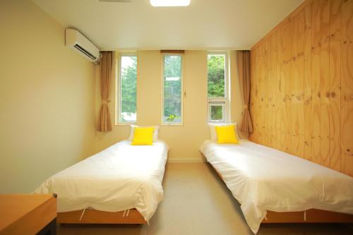 首尔Slow Vibe Myeongdong的带2扇窗户的客房内的2张床