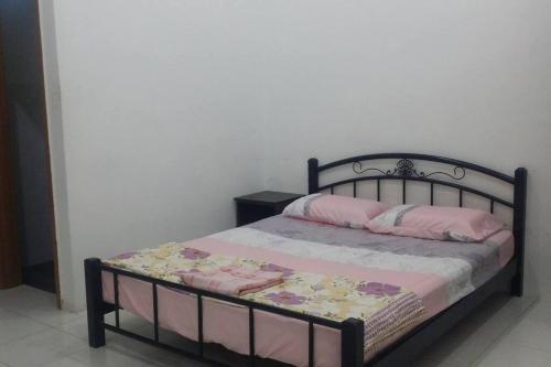 Pokok SenaCozy Homestay in Central Pokok Sena的一张黑色床架和粉红色枕头