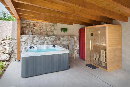马尔切西内Villa Fani-Wellness & Relax的浴室设有热水浴缸,毗邻石墙