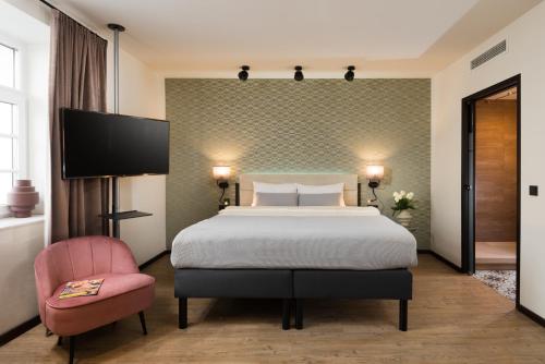 萨尔茨堡master Mirabell的酒店客房,配有一张床和一张粉红色的椅子
