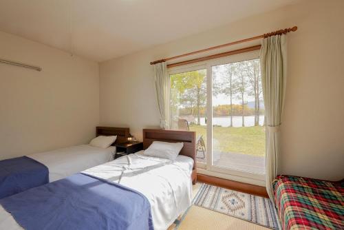 北塩原村Lakeside Hotels Kuore的带大窗户的客房内的两张床