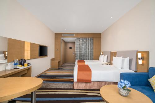 广州蔚徕酒店广州白云机场店(原白云机场智选假日酒店）的酒店客房设有一张大床和一张蓝色的沙发。