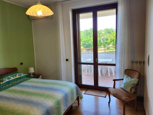 TolloCOLLINA FIORITA的一间卧室设有一张床、一个窗口和一把椅子