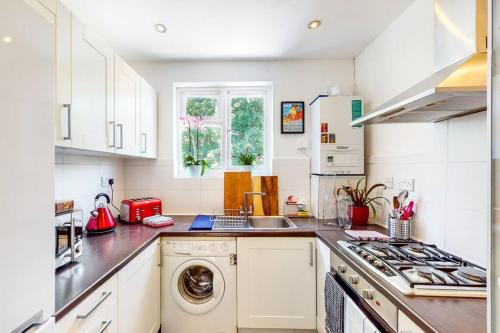 ColindaleModernistic 2 BR maisonette in Kingsbury的厨房配有白色橱柜、洗衣机和烘干机