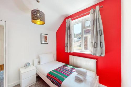 ColindaleModernistic 2 BR maisonette in Kingsbury的红色的卧室设有白色的床和窗户。