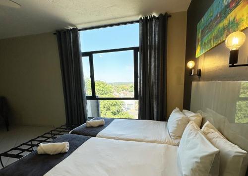 哈拉雷N1 Hotel Samora Machel Harare的一间卧室设有两张床和大窗户