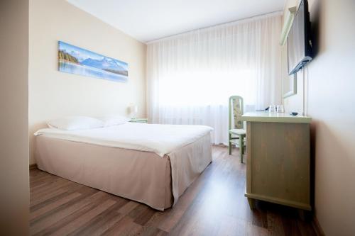 塔林迪曾格尔酒店的卧室配有一张白色大床和电视。