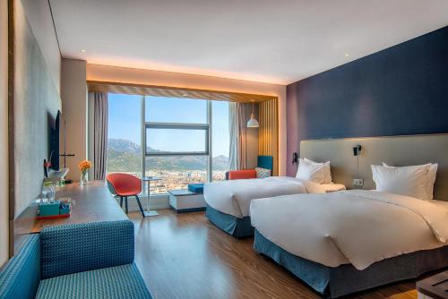 泰安泰安中心智选假日酒店的酒店客房设有两张床和大窗户。