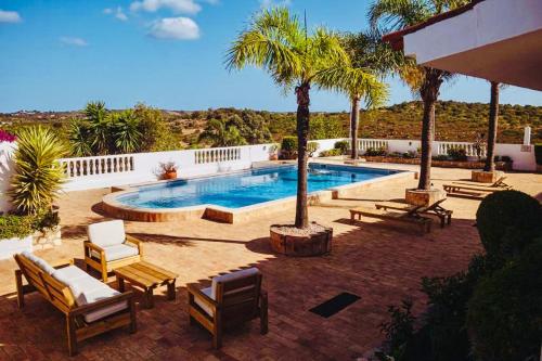 拉戈斯Quinta da Bela Vista的一个带椅子的游泳池,并种植了棕榈树