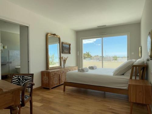 拉格朗德默特La Villa Bord de Mer N02的一间卧室配有一张床、镜子和窗户