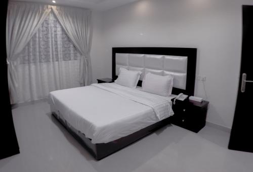 Hotat bani tamimروز للشقق الفندقية的卧室配有一张带白色床单和枕头的大床。
