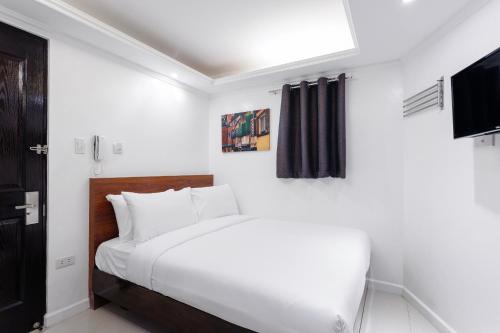 马尼拉NEST NANO SUITES POBLACION-MAKATI的一间白色卧室,配有床和电视