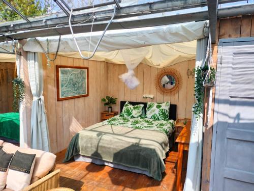 HankVrijstaande accommodatie Glamping de Kas InN的一间卧室配有一张床和天篷