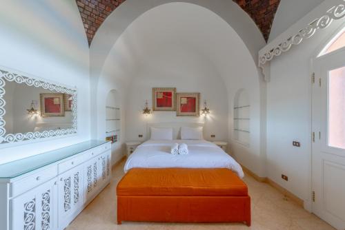 赫尔格达6BR Villa in North Golf El Gouna Private Pool Lagoon Guest house的白色卧室配有一张床和一个橙色的搁脚凳