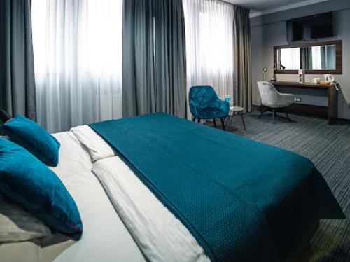 比亚韦斯托克白银酒店的一间卧室配有一张带蓝色毯子的大床