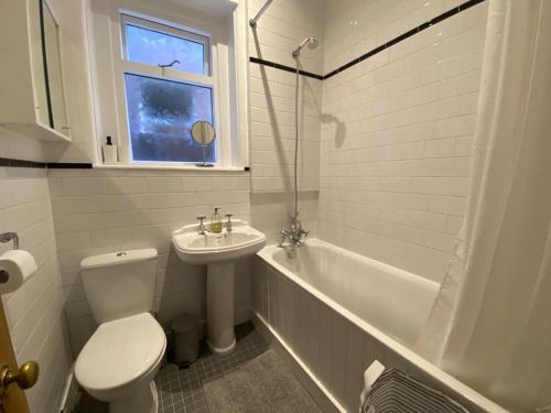 伦敦Beautiful one bed garden flat in Muswell hill的浴室配有卫生间、盥洗盆和浴缸。
