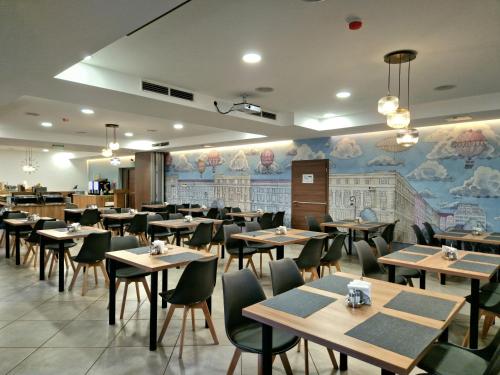 布达佩斯Medos Hotel的一间带桌椅和壁画的餐厅