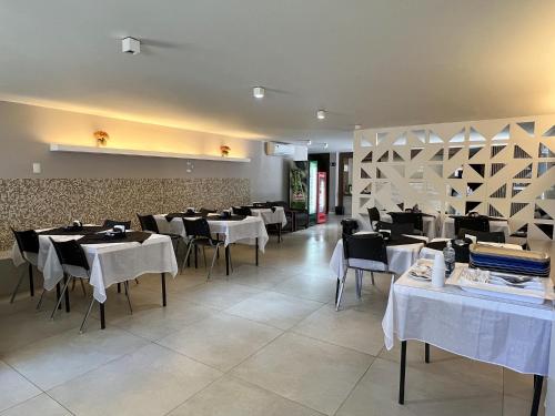 巴西利亚里维埃拉酒店的一间设有白色桌椅和墙壁的用餐室