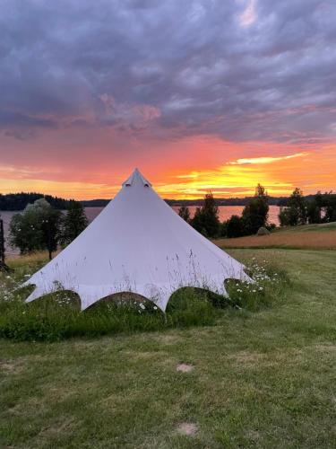Amberhouse Glempings的一片田野上的白色帐篷,背面是日落
