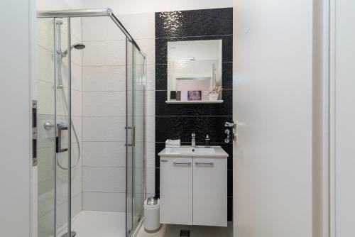 特罗吉尔Apartments Bozan的一间带水槽和玻璃淋浴的浴室