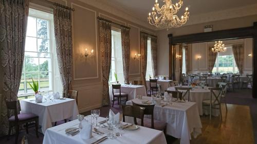 莱克斯利普Leixlip Manor Hotel的餐厅配有白色的桌椅和吊灯