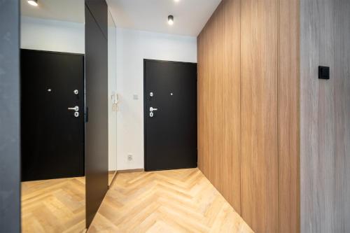 罗兹Apartament Piotrkowska 44 - studio的走廊设有三扇黑色门,铺有木地板