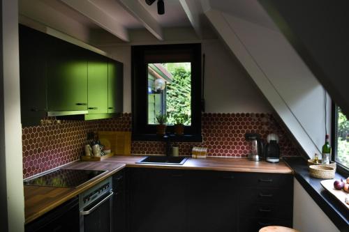 拉纳肯Boshuisje Rekem - Topo的厨房配有绿色橱柜、水槽和窗户