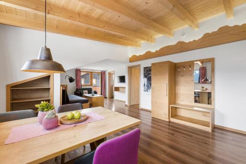 博尔斯特尔朗Berghaus Mucha - Ferienwohnungen - Naturpark Partner的用餐室以及带木桌和紫色椅子的客厅。