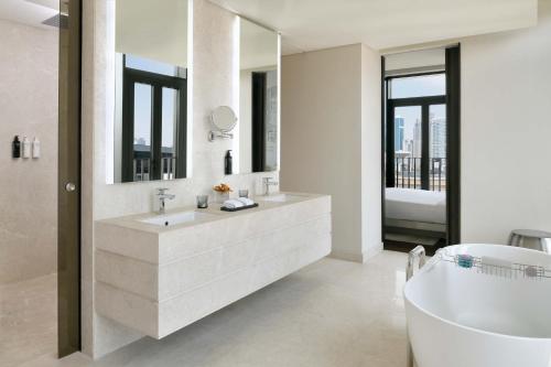 迪拜迪拜城市漫步傲途格精选酒店的白色的浴室设有浴缸和大镜子