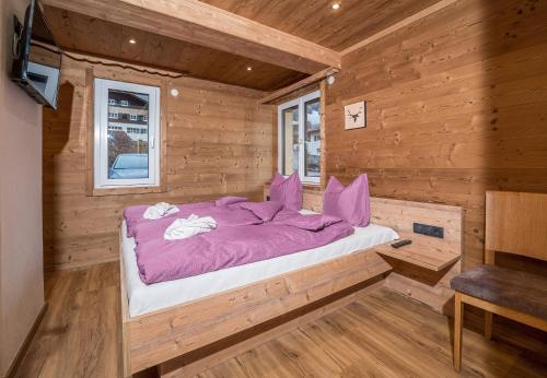 加舒恩Schima Drosa Apartments - Studios - by Pferd auf Wolke的小木屋内的一张床位,配有紫色棉被