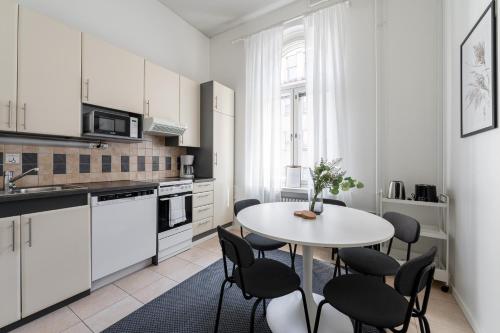 坦佩雷2ndhomes Tampere "Ruuskanen" Apartment - 3 Bedrooms, Best Location & Sauna的白色的厨房配有白色的桌子和椅子