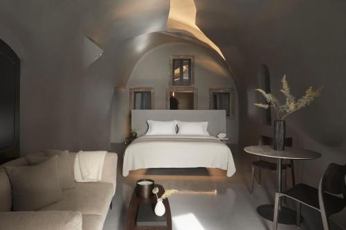 易莫洛林Kivotos Santorini的一间卧室配有一张床,客厅配有沙发