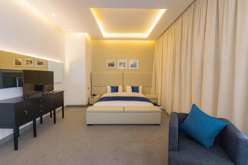 安曼Boho Boutique Hotel Amman的一间卧室配有一张床、一台电视和一张沙发