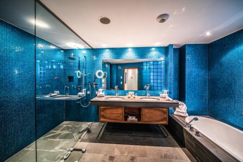 莱奥冈Hotel Krallerhof的浴室配有蓝色瓷砖墙壁、浴缸和水槽。