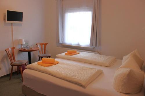 吕本瑙Pension An der Kamske, FZ 5 Familien的一间设有两张床的客房,配有橙色毛巾