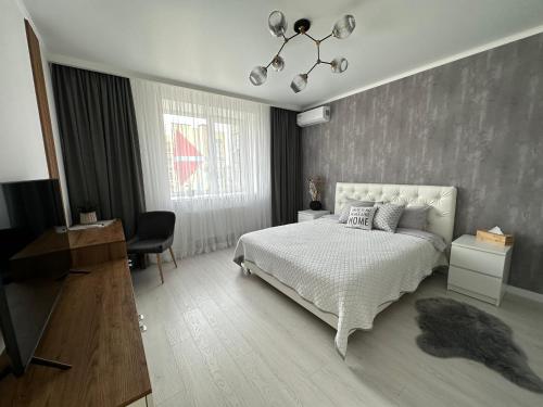 文尼察Comfort Apartment的一间卧室配有一张床、一张书桌和一台电视