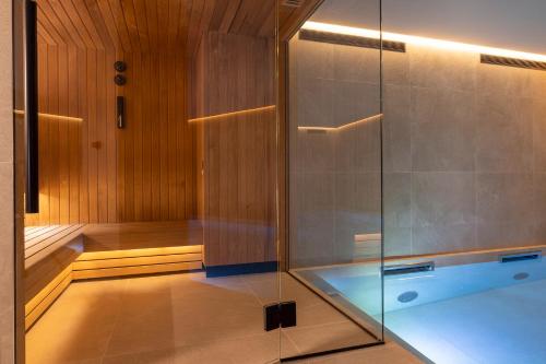 巴黎Hôtel Esté的一间带玻璃淋浴和浴缸的桑拿浴室