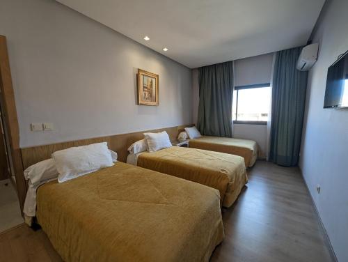 阿尤恩Sahara Line Hotel的酒店客房设有两张床和窗户。