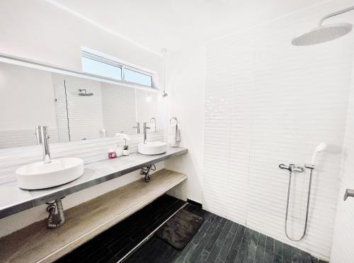 圣玛尔塔Comunidad Calle 13 Hotel Boutique的白色的浴室设有2个盥洗盆和淋浴。