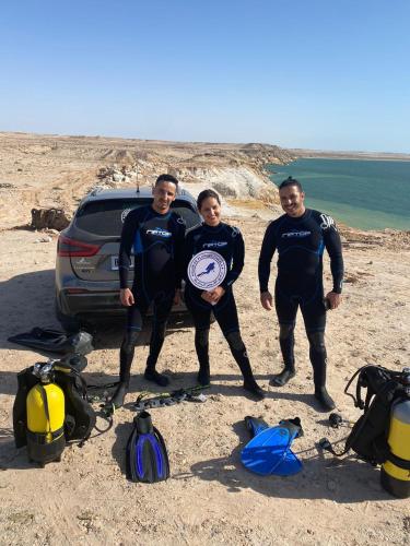 达赫拉DAKHLA DIVING CAMP的一群三人站在海滩上,身着炸薯条