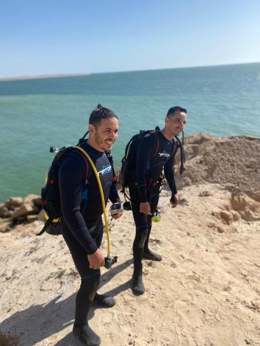 达赫拉DAKHLA DIVING CAMP的两名穿着湿衣的男子在海滩上散步