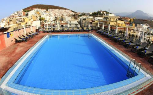 洛斯克里斯蒂亚诺斯Hotel Reveron Plaza的一座带椅子和建筑的大型蓝色游泳池
