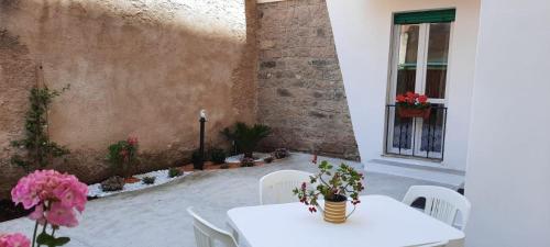 阿尔盖罗La Llua Alghero的庭院里配有白色的桌椅和鲜花