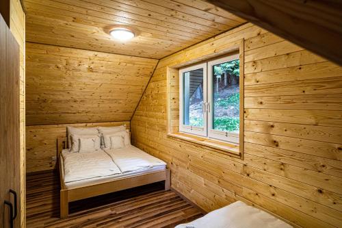 波拉齐克UROCZYSKO-POLAŃCZYK Prywatne Jacuzzi i Sauna w cenie !!!的木制客房的一张小床,设有窗户