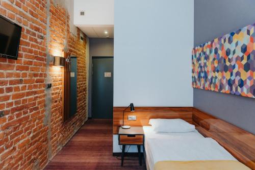 罗兹托巴克罗兹酒店的一间卧室设有一张床和砖墙