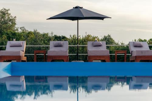 苏卡雷斯Villa Erato的游泳池配有椅子、遮阳伞和遮阳伞