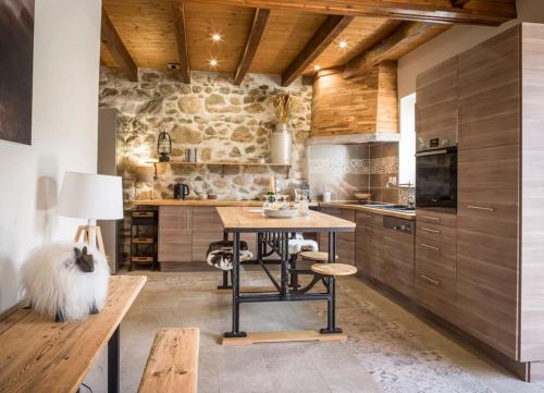 圣若里奥Venez Chez Vous - La Grange du Lac - Vue montagne的厨房配有桌子和石墙