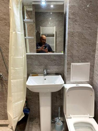 塞凡Aram Guest House的男人拍着带卫生间和水槽的浴室的照片